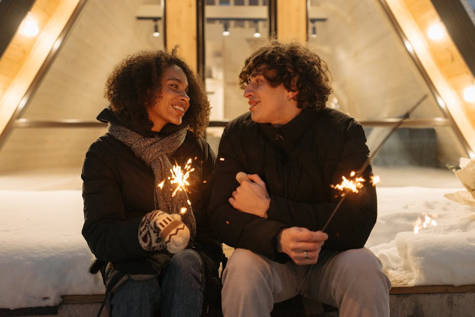 A couple enjoying a romantic winter evening outdoors, sharing sparklers and smiles.
