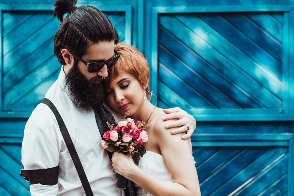 Charming moment of a couple embracing with a bouquet in front of a blue door. Perfect for engagement or wedding themes.