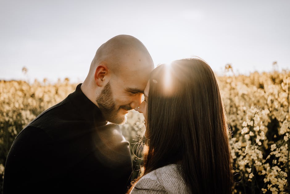 A couple embraces in a sunlit field of flowers, showcasing love and togetherness.