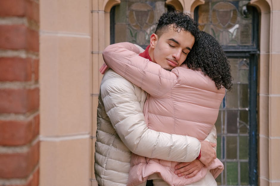 Calm Hispanic couple in casual clothes standing and embracing on street in city in daytime
