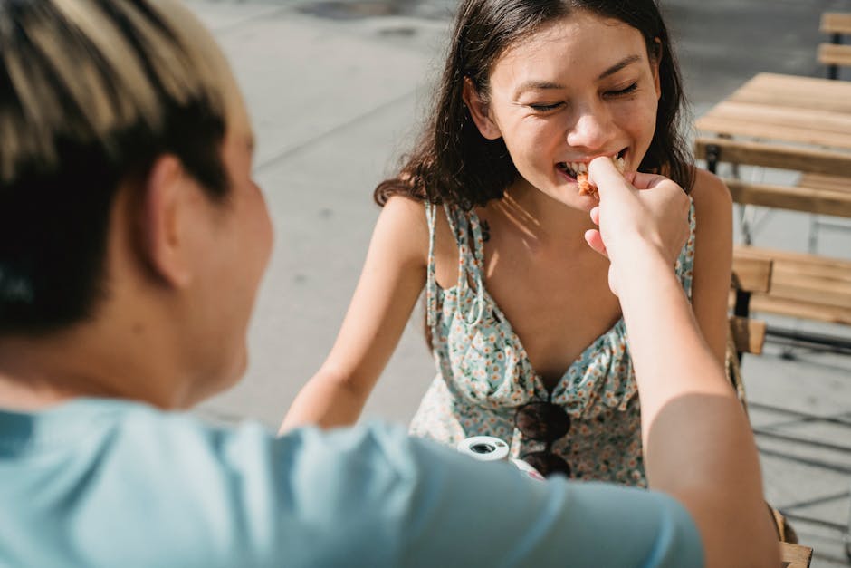 A couple sharing a fun and romantic meal outdoors in the sunlight.