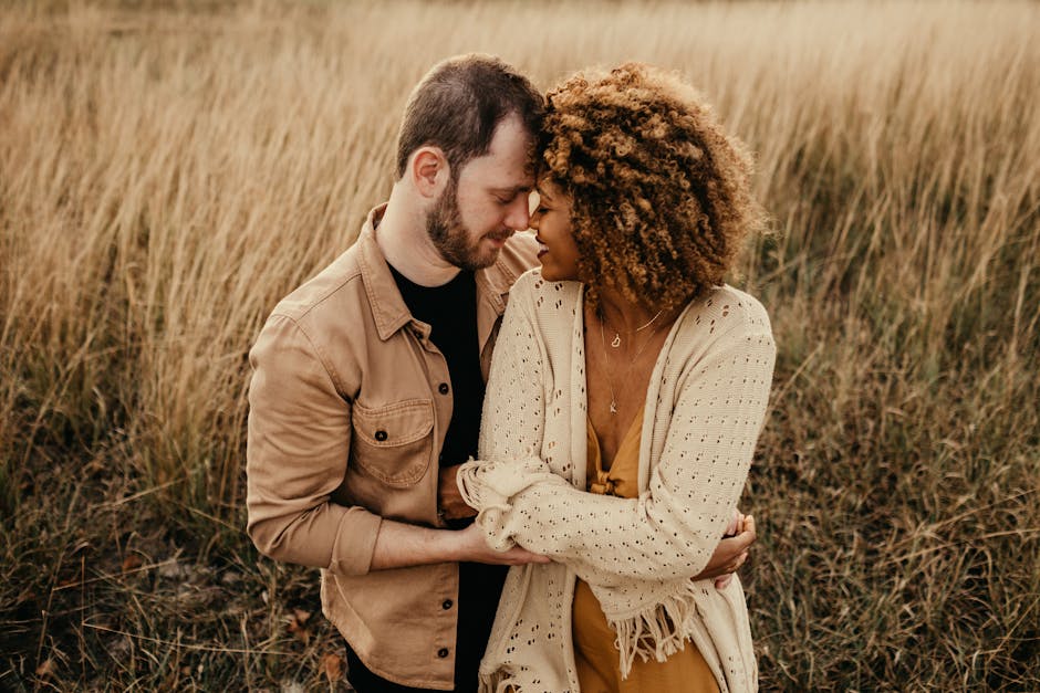 A couple sharing a tender moment in a grassy field, capturing love and connection.