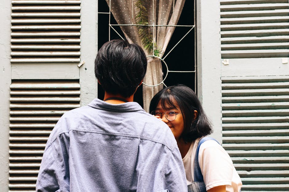 A young couple sharing a candid moment outdoors, expressing affection and joy.