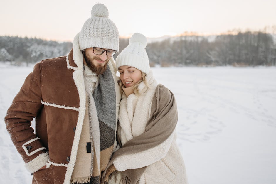 A couple enjoying a snowy winter day outdoors, wrapped in warm clothing.
