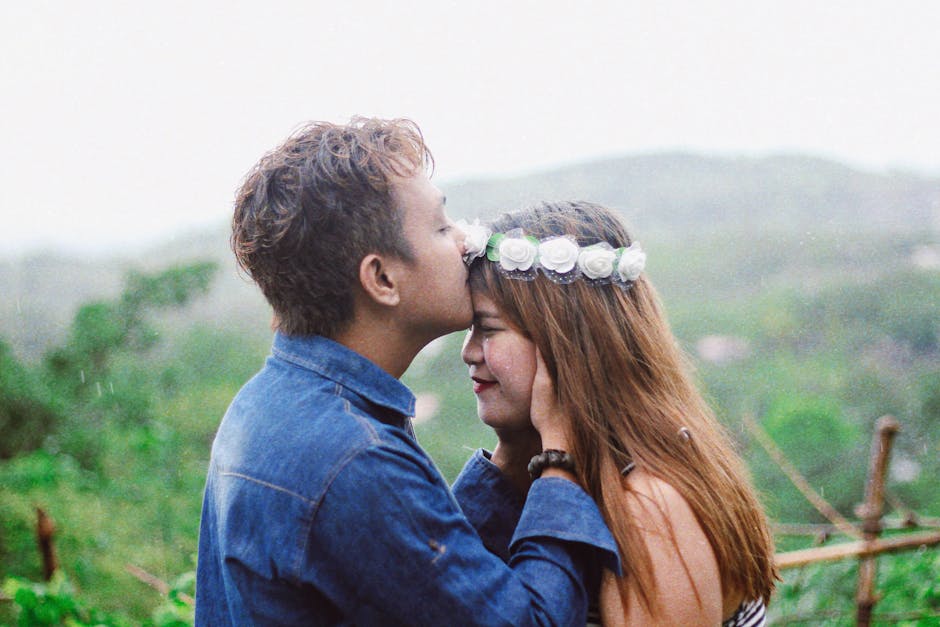 Young couple sharing a tender moment outdoors in a lush, peaceful landscape.