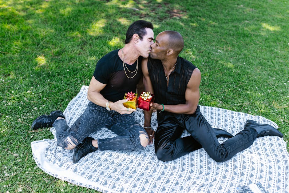 A loving couple shares a romantic moment on a picnic blanket, exchanging gifts and a kiss.
