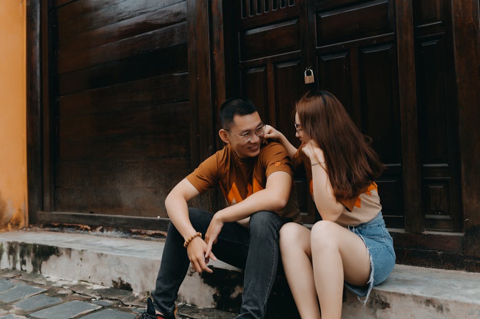 Happy young ethnic couple speaking and smiling while looking at each other on urban street near building