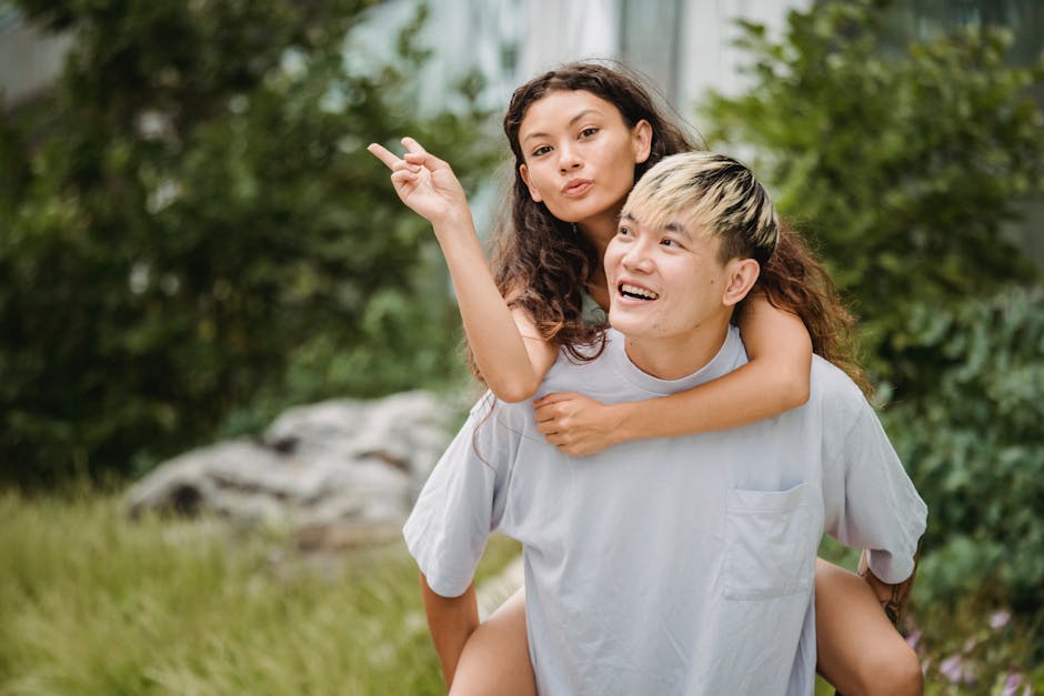 Young couple having fun with piggyback ride in a park, expressing love and joy.
