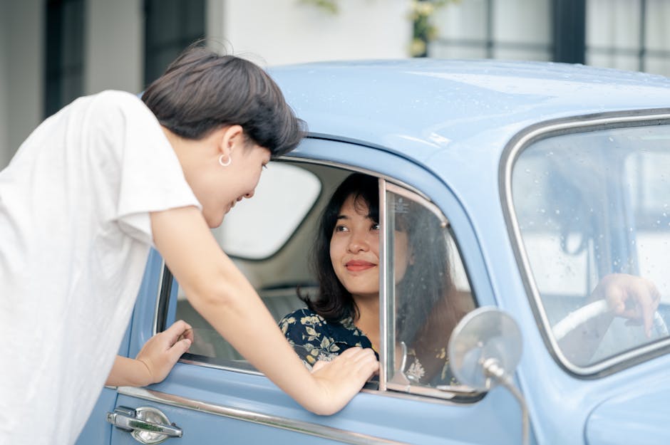 A couple shares a happy moment while interacting through a vintage blue car window, showcasing love.
