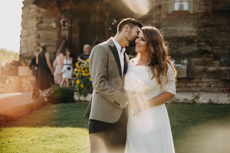 Beautiful outdoor wedding with bride and groom embracing in warm sunlight.