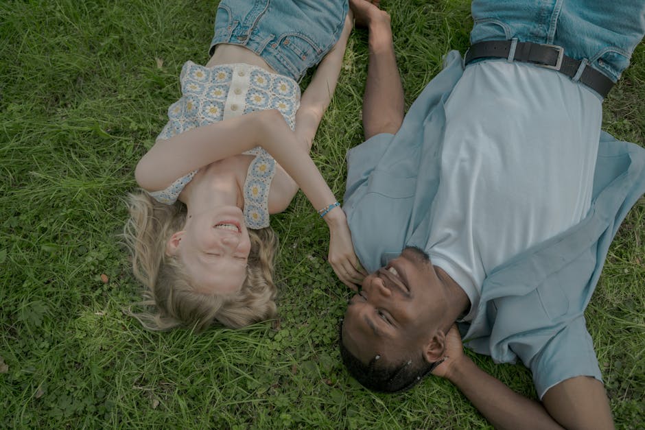 A happy couple lying on the grass enjoying a summer day in the park.