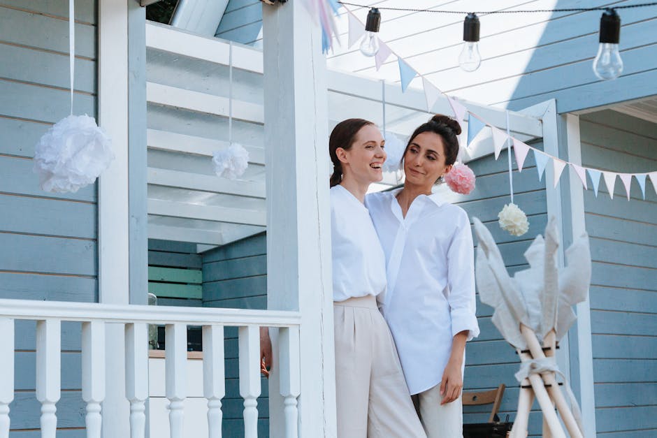 Smiling couple embraces under festive decorations on a sunlit porch, exuding happiness and love.