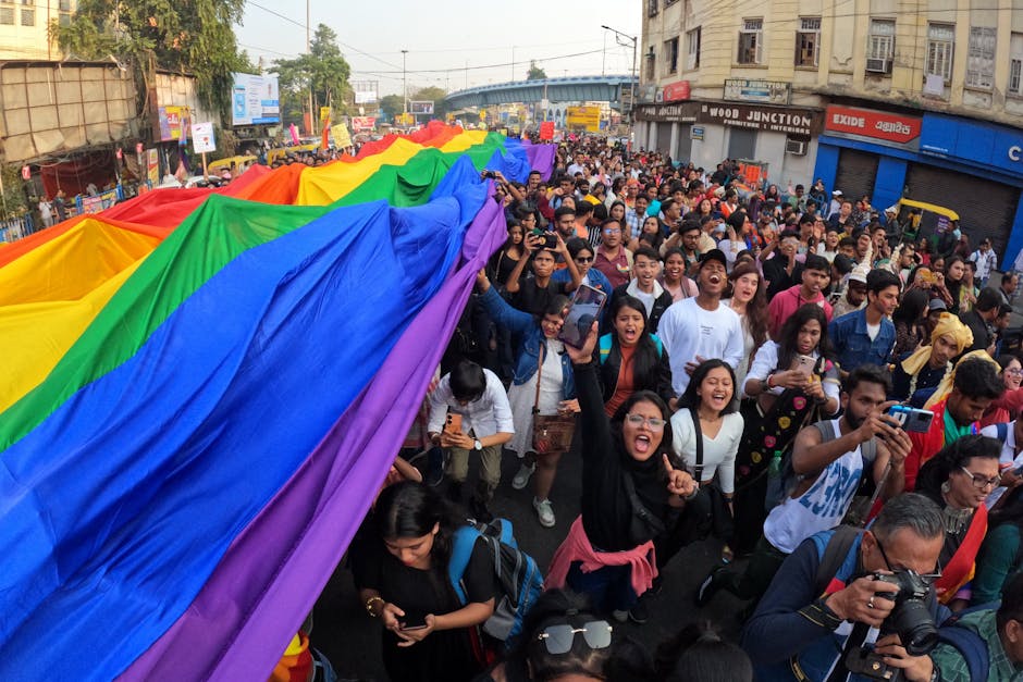 Lively pride parade in Kolkata with colorful rainbow flags and a joyful crowd.