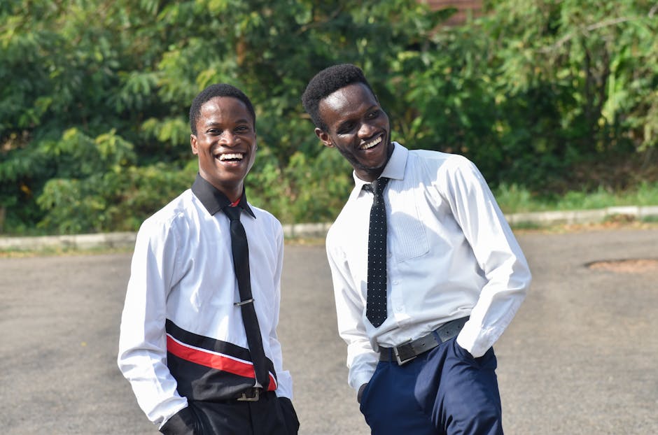 Two young men share a cheerful moment outdoors in Ife, Osun, Nigeria, dressed in formal attire.