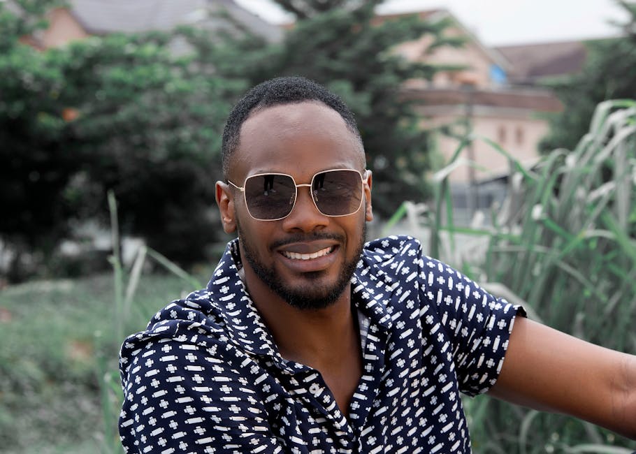 Portrait of a stylish black man with sunglasses smiling outdoors in Lagos, Nigeria.
