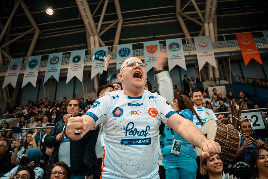 Passionate sports supporter in a crowded indoor arena, cheering with excitement.