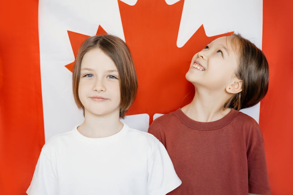 Two children in front of a Canadian flag, expressing joy and national pride.