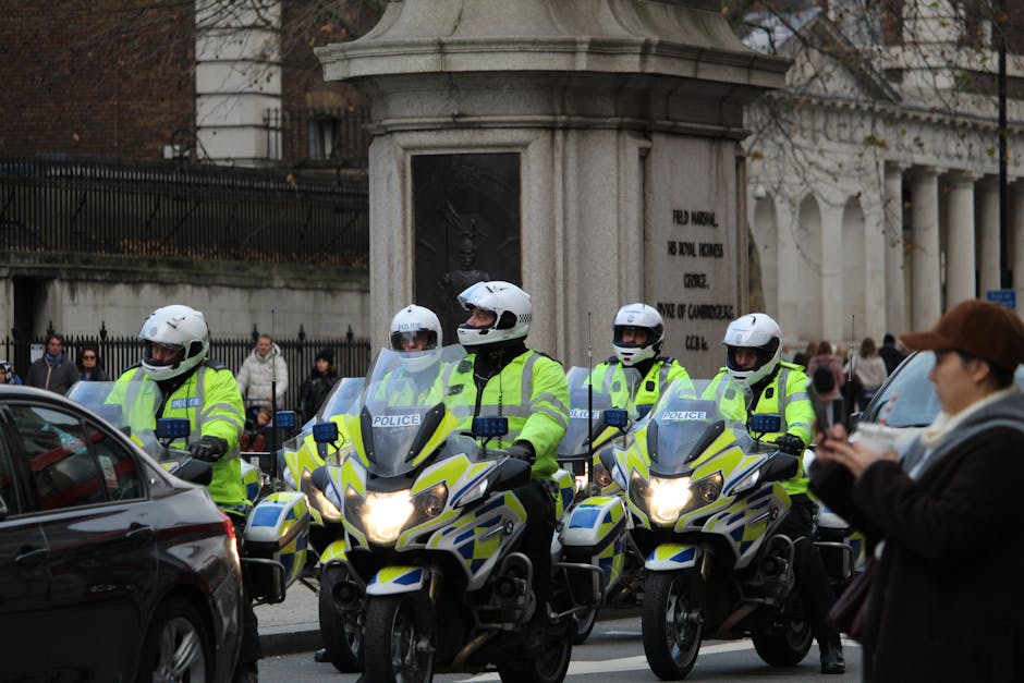 Police officers on motorcycles patrolling an urban intersection with onlookers.