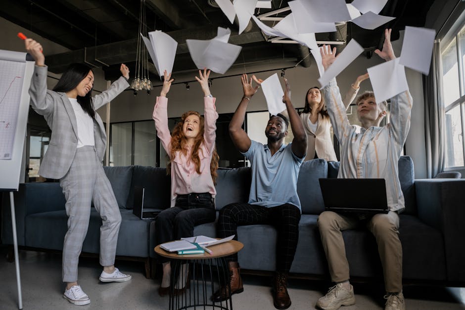 A diverse group of coworkers celebrating success by throwing papers in an office.