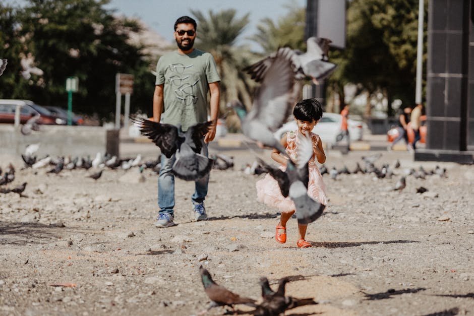 A joyful father and daughter enjoy an outdoor day with pigeons in Muscat, Oman.