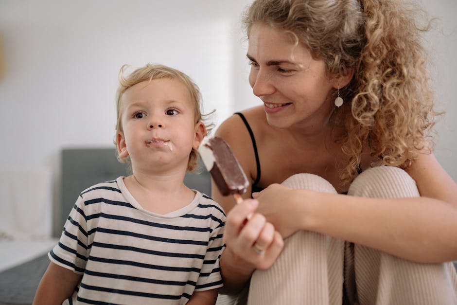 A mother and her young son share a joyful moment eating ice cream together indoors.