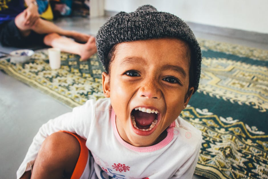 A cheerful child laughing inside while wearing a beanie, exuding warmth and happiness.