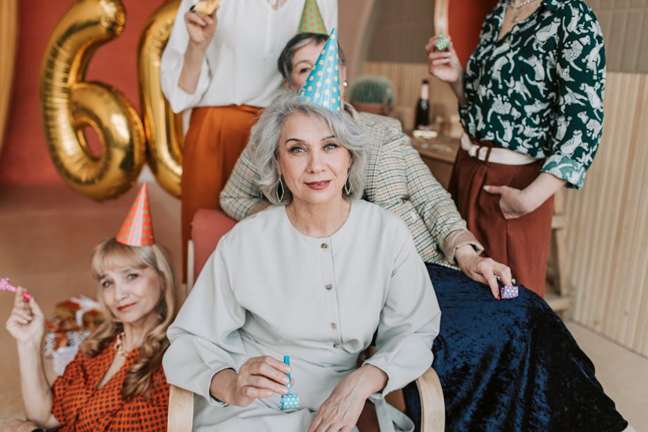 Senior women celebrating a 60th birthday indoors with party hats and balloons.