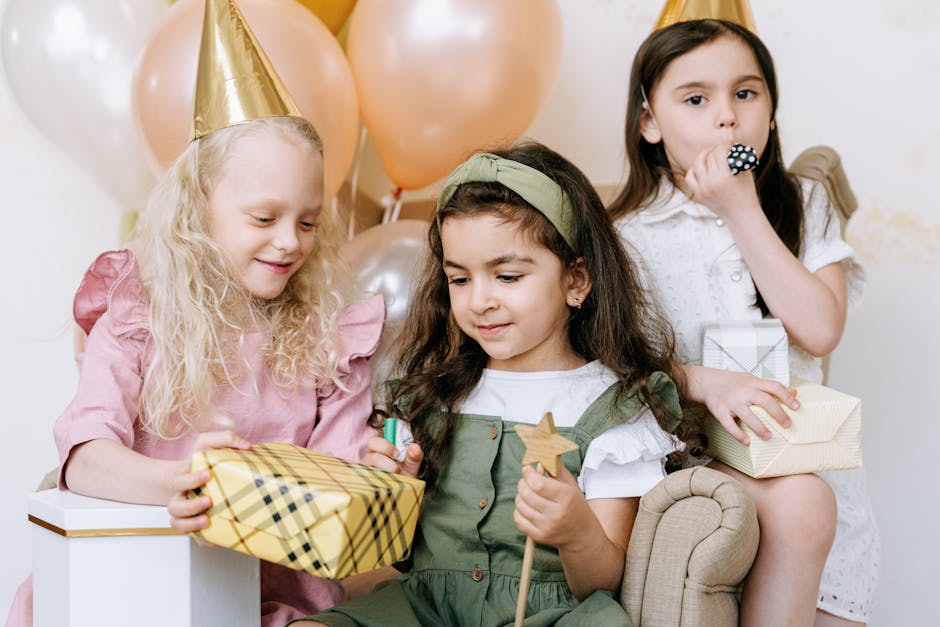 Three young girls celebrate a birthday with gifts, balloons, and party hats, capturing a moment of joyful togetherness.