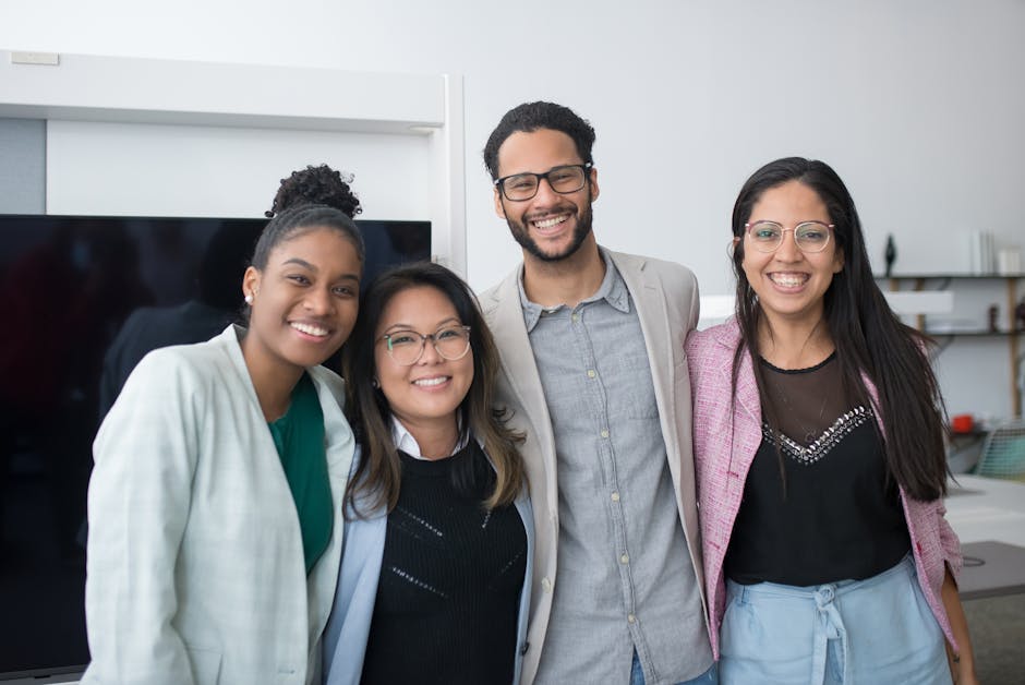 A diverse group of coworkers smiling in a modern office environment, showcasing teamwork and collaboration.