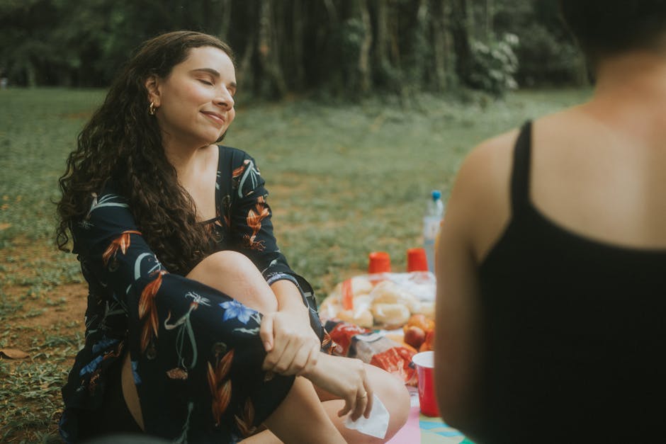 Two women enjoying a peaceful summer picnic outdoors, feeling relaxed and happy.