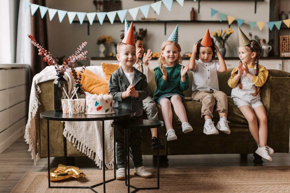 Group of children celebrating a birthday with cake and party hats indoors.