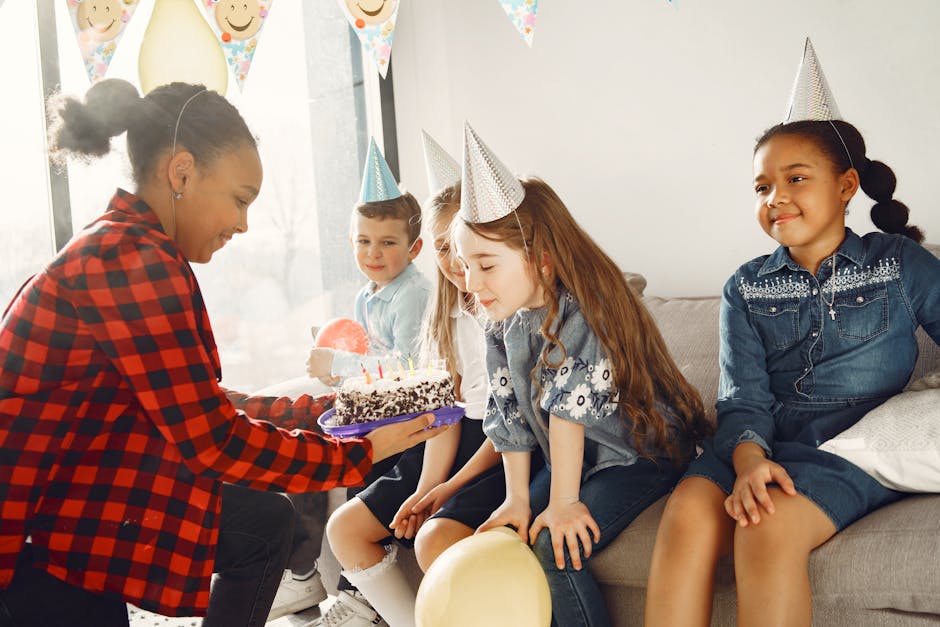 Happy group of kids celebrating a birthday with cake and party hats indoors.