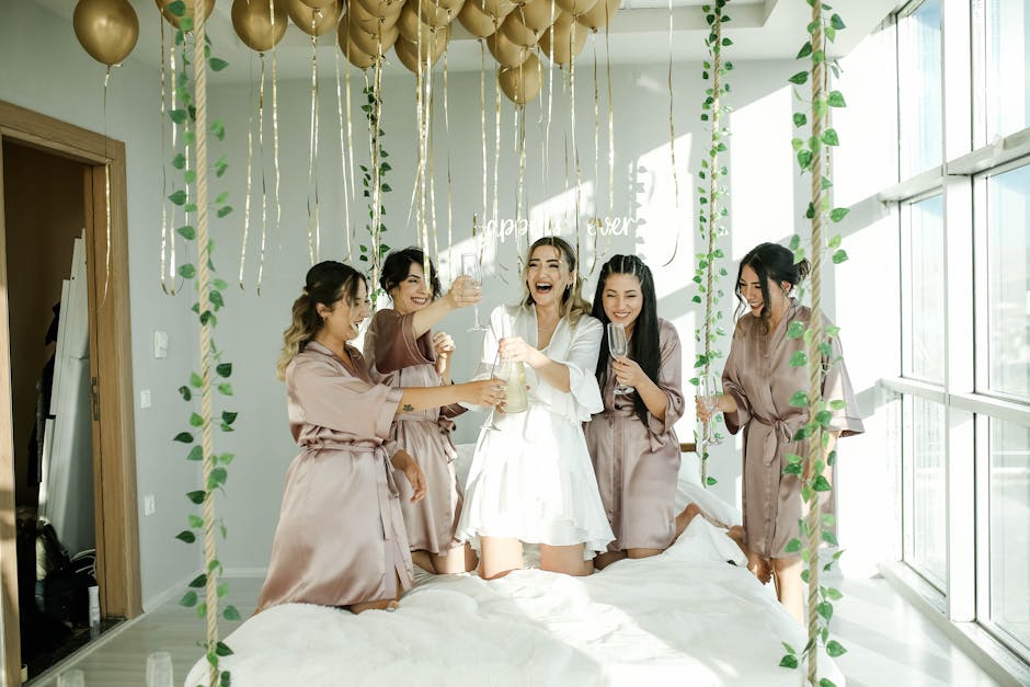 A happy bride enjoys a joyful moment with bridesmaids indoors, surrounded by gold balloons.