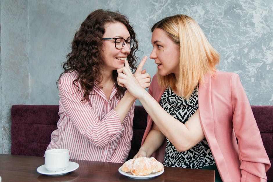 Two friends sharing a playful moment over coffee and pastry in a cozy café setting.