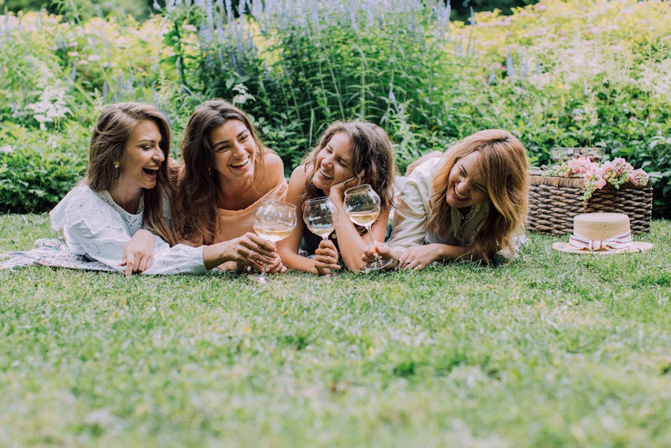 A group of women enjoying a cheerful picnic in a lush garden, toasting with wine glasses.