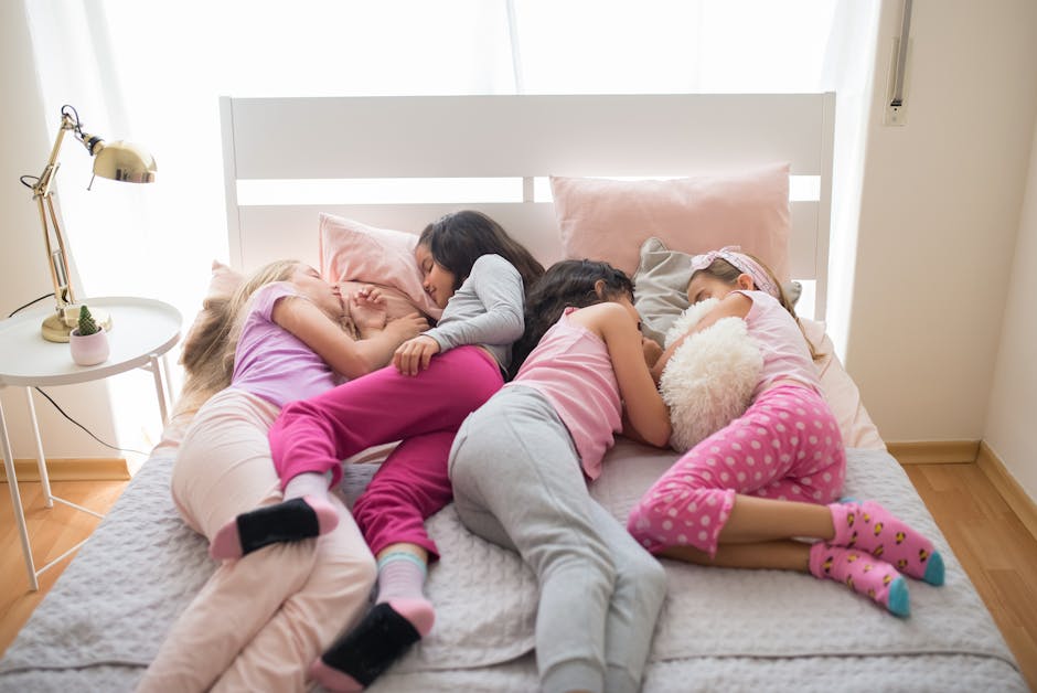 Four young girls enjoy a playful sleepover, dressed in colorful pajamas, sharing their fun and dreams.