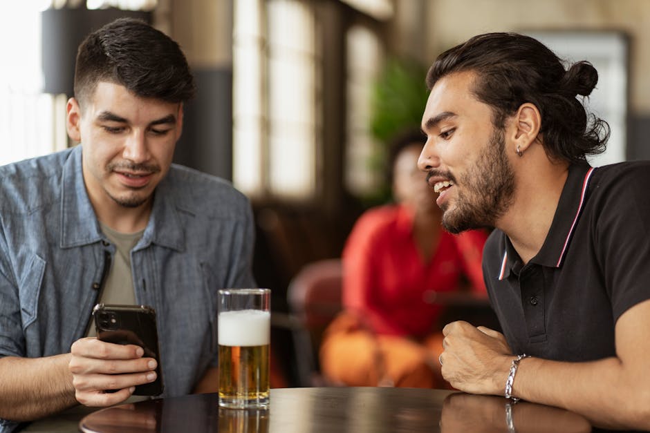 Two young men enjoying a casual conversation over drinks in a cozy pub setting.
