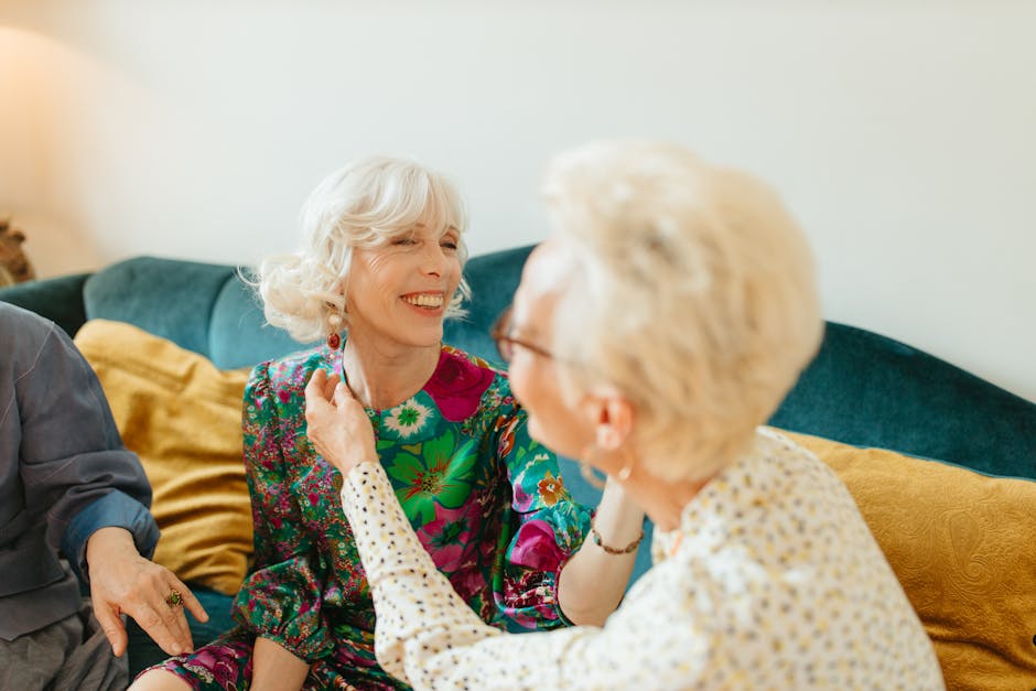 Two senior women sharing a joyful moment in a comfortable living room setting, symbolizing friendship.