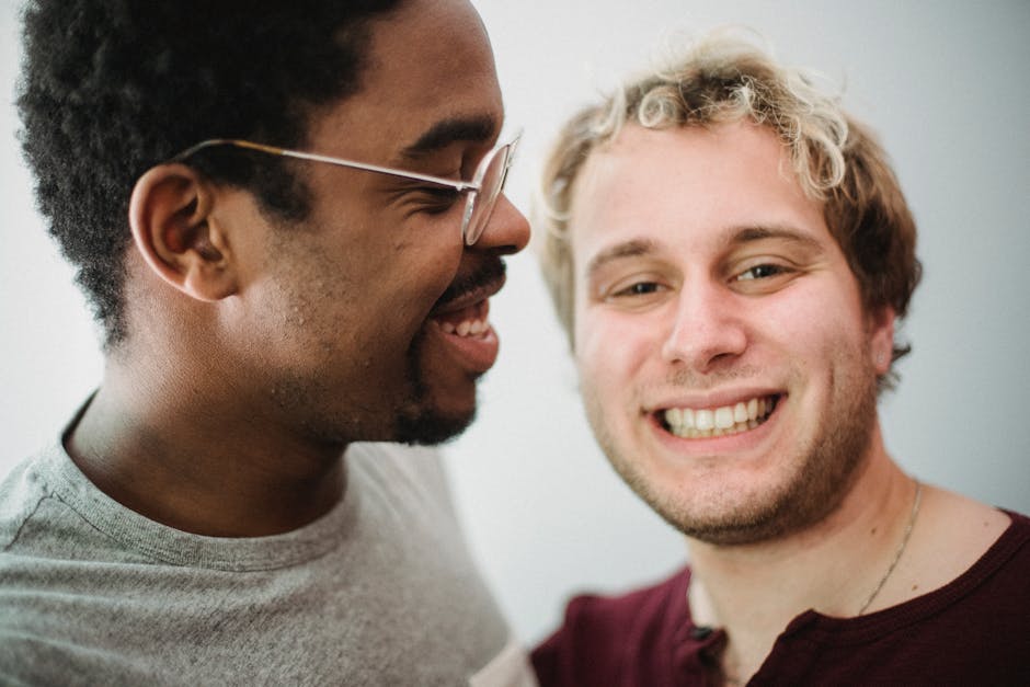 Two friends sharing a joyful moment indoors with bright smiles on a white background.