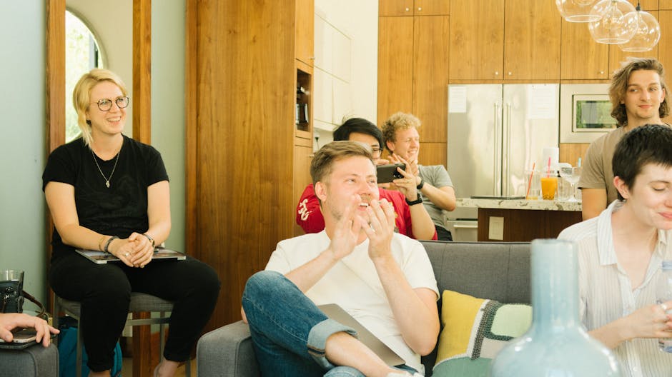A group of diverse colleagues enjoying a casual meeting indoors with laughter and discussion.