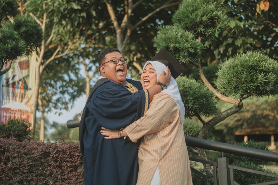 Joyful couple celebrating graduation in an outdoor setting with lush greenery in Putrajaya, Malaysia.