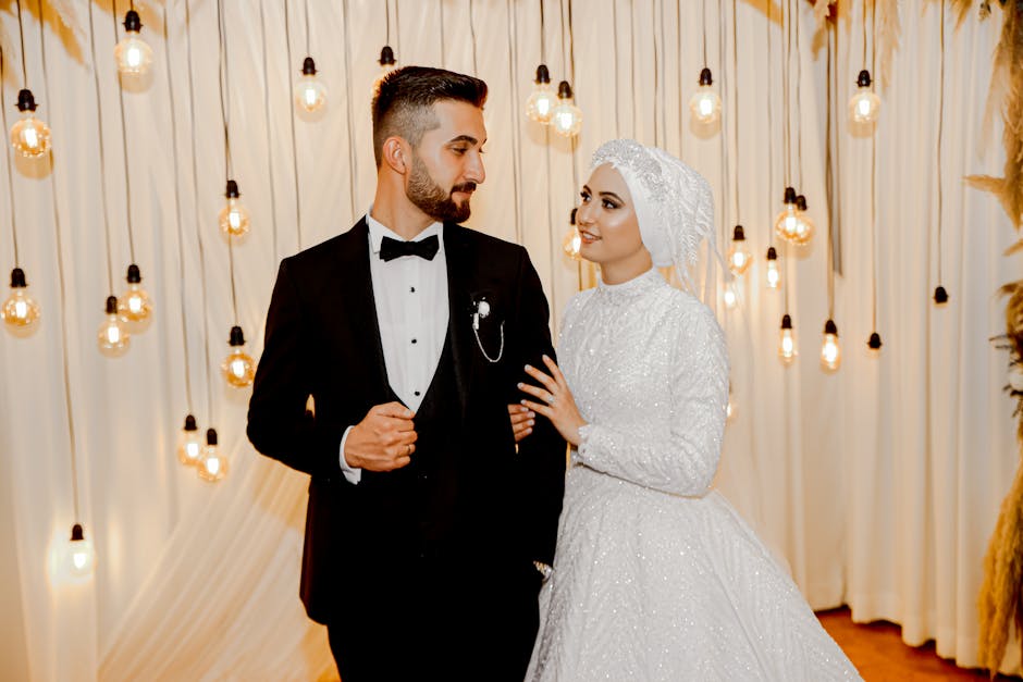 An elegant indoor wedding portrait of a newlywed couple posing with vintage lighting decor.