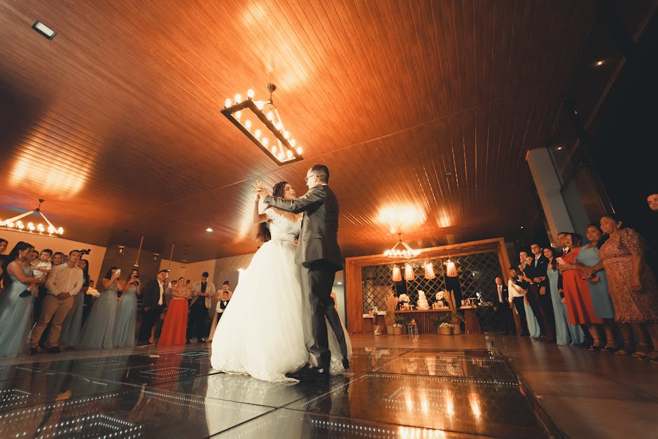 Bride and groom share a magical first dance surrounded by guests at a wedding reception.