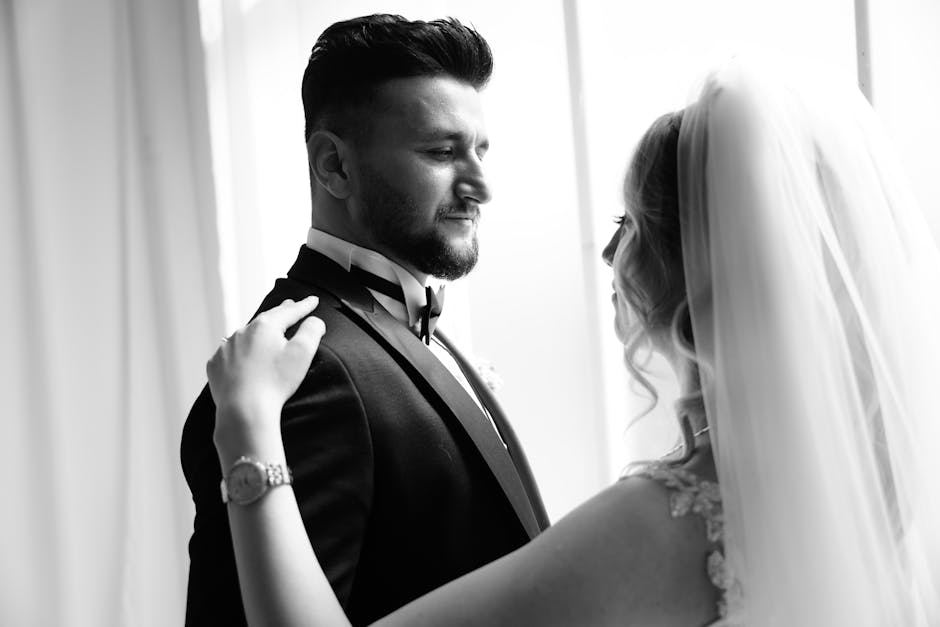 A timeless black and white photo capturing a bride and groom embracing indoors.