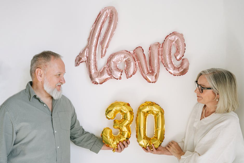 Elderly couple celebrating 30th anniversary with love-themed balloons.