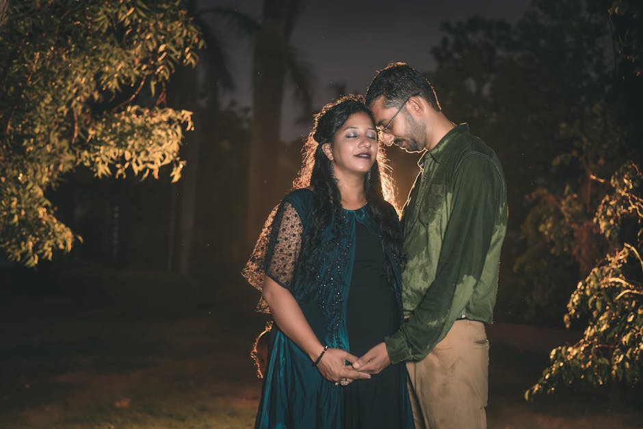 A romantic outdoor night portrait of a pregnant couple lovingly embracing in Dhari, India.