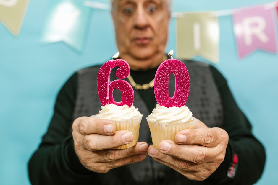 Senior man celebrating 60th birthday with cupcakes and candles indoors.