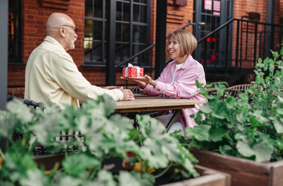 Elderly couple enjoying a special moment exchanging gifts at an outdoor café.