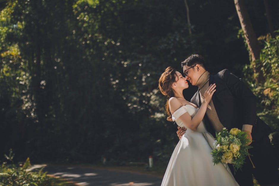 A wedding couple sharing a tender kiss in a lush forest setting in Dalat.