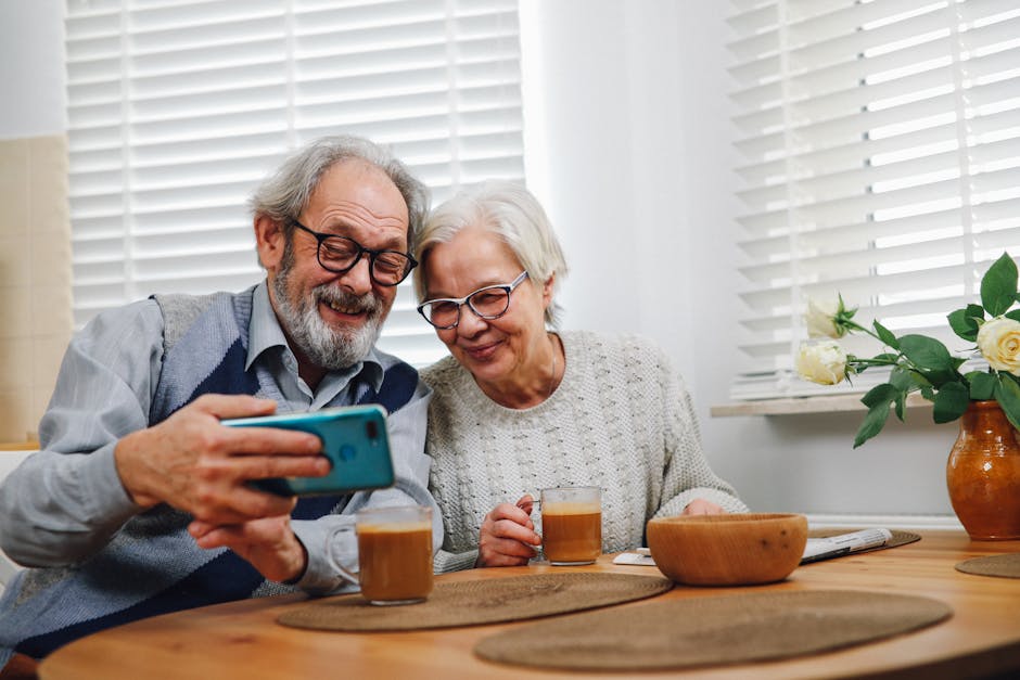 Elderly couple enjoying coffee and taking a selfie together in a cozy kitchen setting.